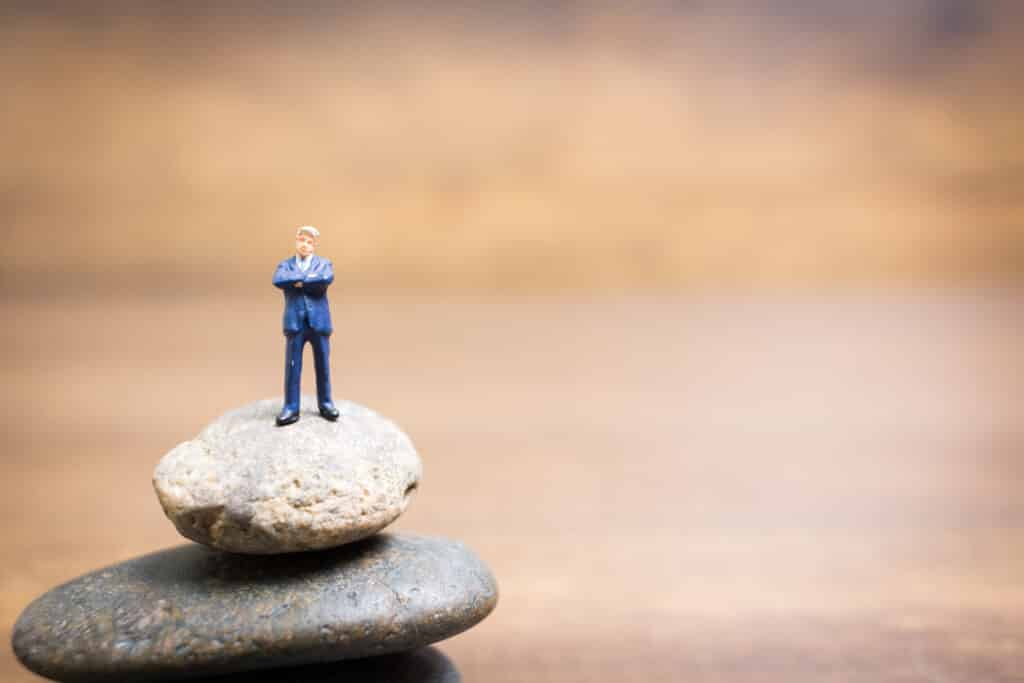 Miniature people : Businessman standing on stone , Challenges and risks Concept